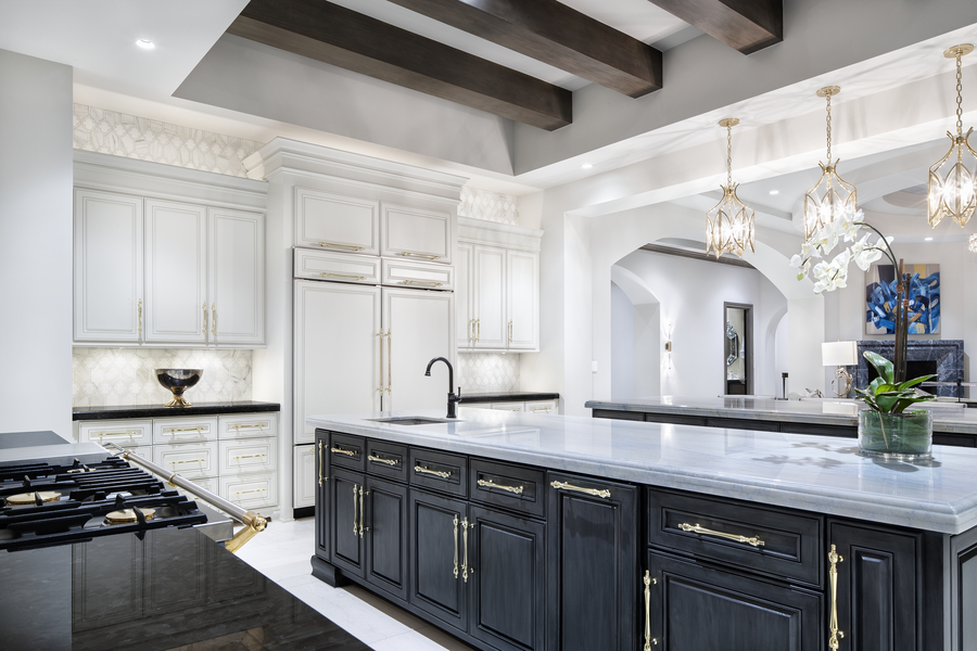 A luxury kitchen with custom cabinetry and layered lighting, featuring pendant lights over a large island, recessed ceiling lights, and elegant finishes that highlight the space’s architectural details.